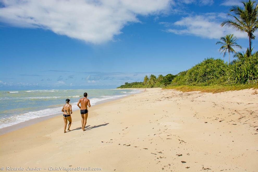 Imagem de casal correndo na beira da Praia de Itapororoca.